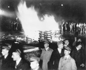 Gut gelaunte Verbindungsstudenten laufen auf dem Berliner Opernplatz am gerade entzündeten Scheiterhaufen vorbei.